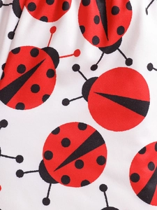 Close-up of cute red ladybug print on white cotton fabric for kids' summer outfit