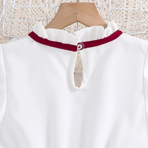 Detailed view of white ruffle collar with red velvet ribbon and purple button on back