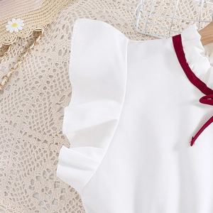 Detail of red ruffle collar and bow on white dress with flutter sleeves for girls