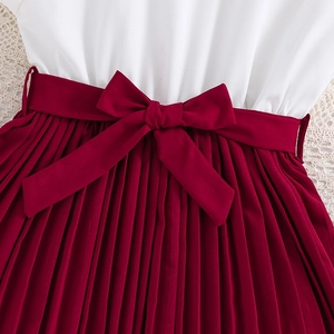 Detail of red pleated skirt with bow waistband and white top for young girls