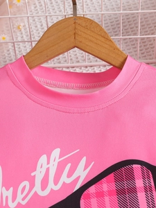 Pink crewneck t-shirt for girls featuring pretty script and plaid heart on wood hanger