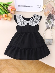 Close-up of baby girl dress with white floral lace collar and ribbed black fabric