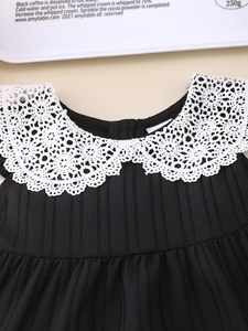Detail of girls' black ribbed dress featuring white hollow lace collar and crochet pattern