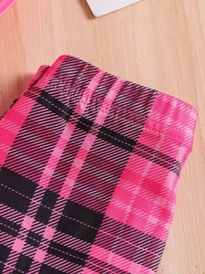 Girls summer pink and black plaid pants set with elastic waistband on wood background