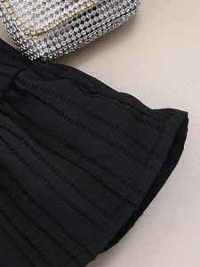Close-up of ribbed knit texture with shimmering sequined accessory on dress