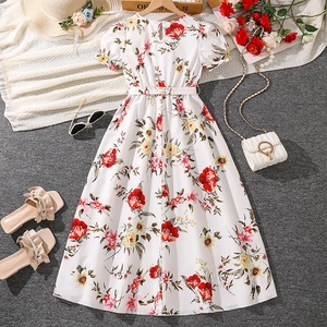 Flat lay of girl's floral summer dress with straw hat, sunglasses, and chain handbag