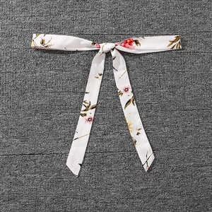 Detail of floral printed sash bow with pink flowers and olive leaves on white fabric