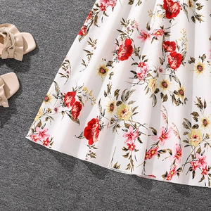 Detail of floral printed white dress hem with red flowers and lightweight summer fabric