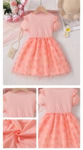 Detail of pink girls' tulle dress featuring heart patterns and ruffled short sleeves