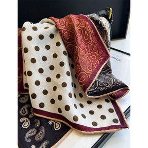 Detail view of silk scarf with paisley patterns and polka dots draped on a bag