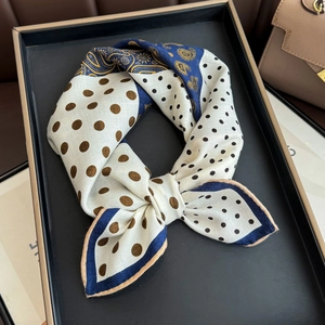 Close-up of silk scarf with polka dots and golden paisley patterns on metal tray