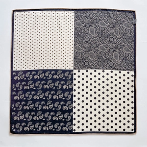Detail of silk square scarf featuring navy paisley and polka dot patterns with hand-rolled edges