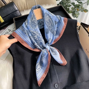 Sky blue paisley chiffon square scarf with brown border tied elegantly on a black vest
