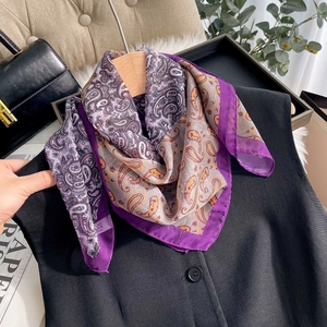 Élégant foulard en soie à imprimé cachemire violet sur un gilet de costume noir sur cintre