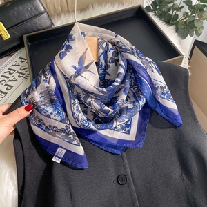 Elegant blue and white floral chiffon scarf draped on a suit for a stylish look