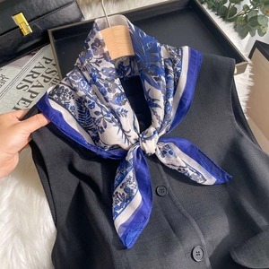 Elegant floral print silk chiffon scarf in blue and white on a black suit vest