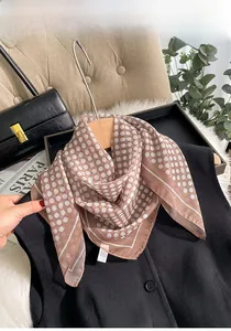 Détail d'un foulard en soie à pois marron rose attaché à un sac à main noir élégant