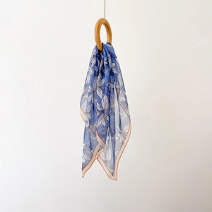 Gros plan d'un foulard en mousseline bleue à motif de lys sur un anneau en bois
