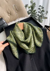 Detail view of grass green silk chiffon scarf with vintage patterns on a wooden hanger
