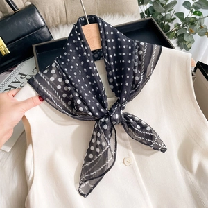 Elegant black and white polka dot chiffon silk scarf styled with a white vest on a hanger