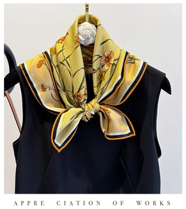 Détail d'une écharpe en soie jaune avec imprimé floral et bordure à rayures bicolores