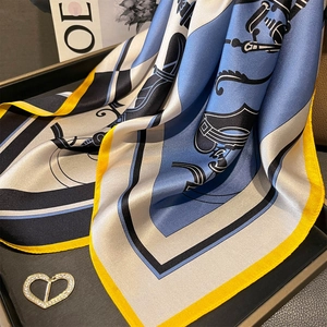 Detail of silk scarf with geometric patterns and heart-shaped metal buckle on tray