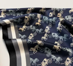 Detail of the high-quality edge stitching on a navy silk scarf with horse carriage pattern