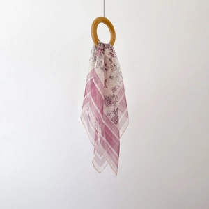 Elegant floral chiffon square scarf in pink and purple tones hanging through a wooden ring