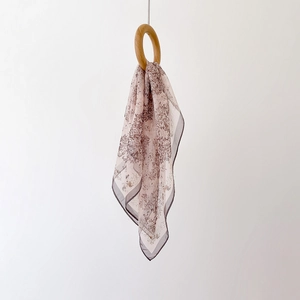 Detail of floral print chiffon scarf draped through a wooden ring with vintage brown pattern