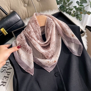Retro floral print chiffon scarf draped on a wooden hanger with a stylish black vest