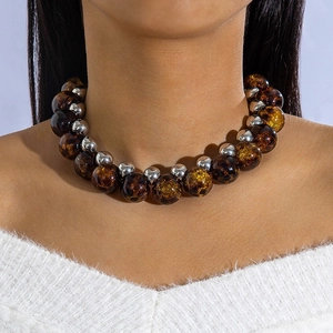 Close-up of oversized amber-style beads and silver spheres on a modern statement necklace