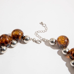 Detail view of amber beads and silver metal spheres with lobster clasp and extension chain
