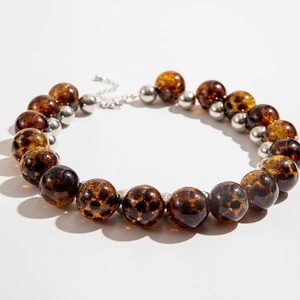 Detail of irregular amber-style brown patterned beads and silver metal spacer beads on a necklace