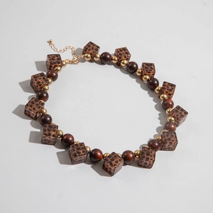 Detail of necklace with leopard print resin beads and dark wood beads on grey background
