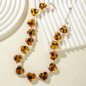 Detail of amber heart resin beads and white pearls on a minimalist jewelry stand