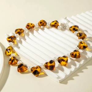 Detail of heart-shaped tortoiseshell resin beads and white pearls on a geometric necklace