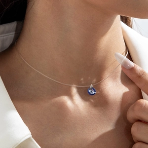 Détail du collier invisible avec pendentif larme bleue flottante sur un fil en nylon