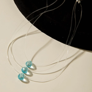 Vue de près de trois colliers invisibles en nylon avec pendentifs cristal bleu ciel facetté