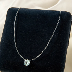 Gros plan du pendentif en pierre bleue sur un collier invisible transparent
