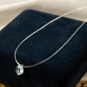 Détail d'un pendentif en cristal bleu clair sur un fil invisible pour femmes