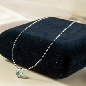 Vue détaillée du collier en fil de pêche invisible avec une pierre gemme bleue facettée