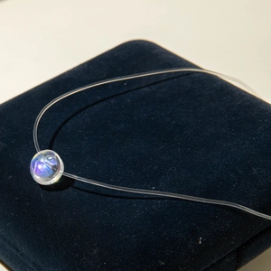 Vue macro d'une perle iridescente sur un collier invisible en fil de pêche transparent