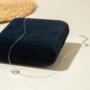 Détail d'un collier invisible en fil de pêche avec pendentif perle sur boîte en velours
