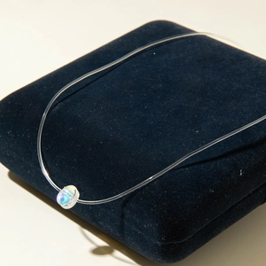 Détail du collier invisible minimaliste avec pendentif goutte d'eau irisée raffiné