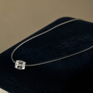 Gros plan du collier invisible avec pendentif en cristal sur un support en velours