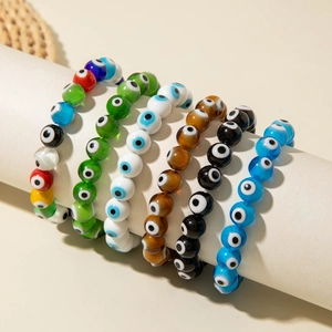 Detail of colorful Evil Eye beaded stretch bracelets on a white display cylinder