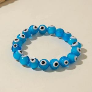 Close-up of bohemian blue evil eye beaded stretch bracelet on a clean beige background