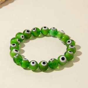 Macro shot of green translucent beads with evil eye patterns on an elastic bracelet