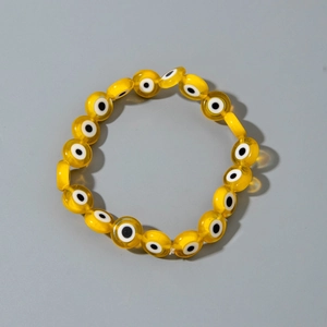 Detail of yellow translucent evil eye beads on a flexible elastic charm bracelet