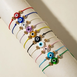 Set of ten colorful evil eye woven bracelets with golden beads on display stand